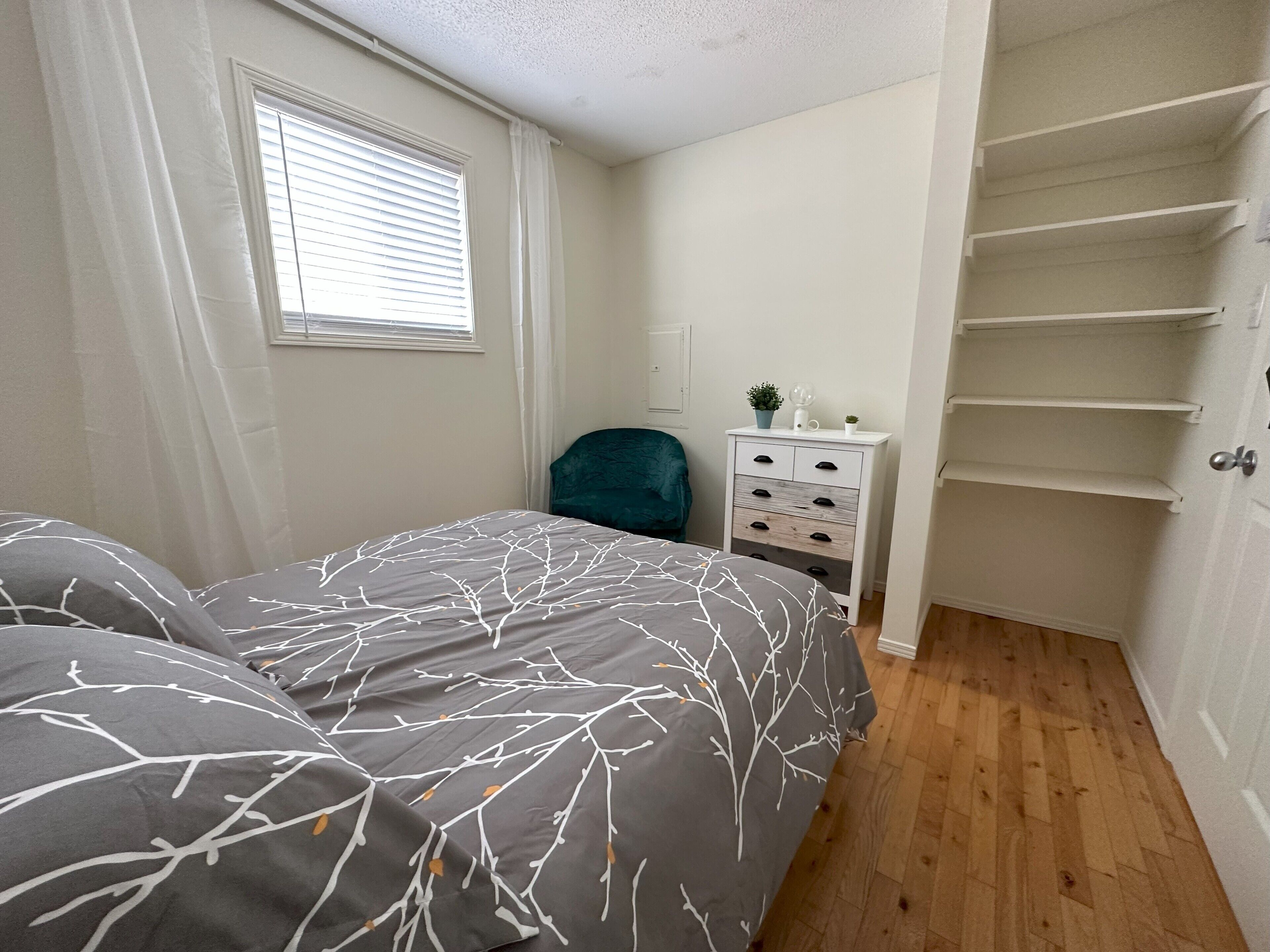 A bedroom with a bed, a nightstand, a dresser, and a closet.