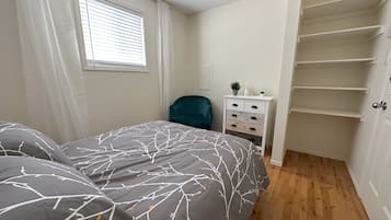 A bedroom with a bed, a nightstand, a dresser, and a closet.