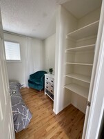 A bedroom with a bed, a chair, a dresser, and a closet.