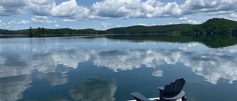 Un lago tranquilo con un muelle y una silla.