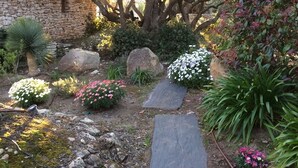 A garden with a stone wall, various plants, and a stone pathway. - Villa Bonifacio Les Maquisardes (Bonifacio)