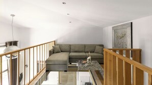 A modern living room with a sectional sofa, a glass coffee table, and a wooden staircase railing. - Villa Bonifacio Les Maquisardes (Bonifacio)
