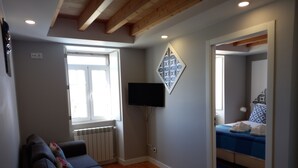 A modern room with a sofa, a bed, a TV, and a decorative wall piece. - Apartment with sea view - Azenhas do mar (NEW) (Colares)