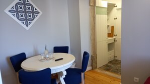 A dining area with a round table, blue chairs, and a decorative wall piece. - Apartment with sea view - Azenhas do mar (NEW) (Colares)