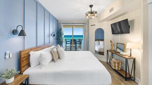 Un dormitorio con una cama grande, televisión, escritorio y vista al océano.
