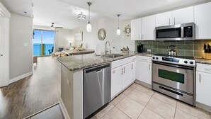 Una cocina moderna con electrodomésticos de acero inoxidable, encimera de granito y vistas al exterior.