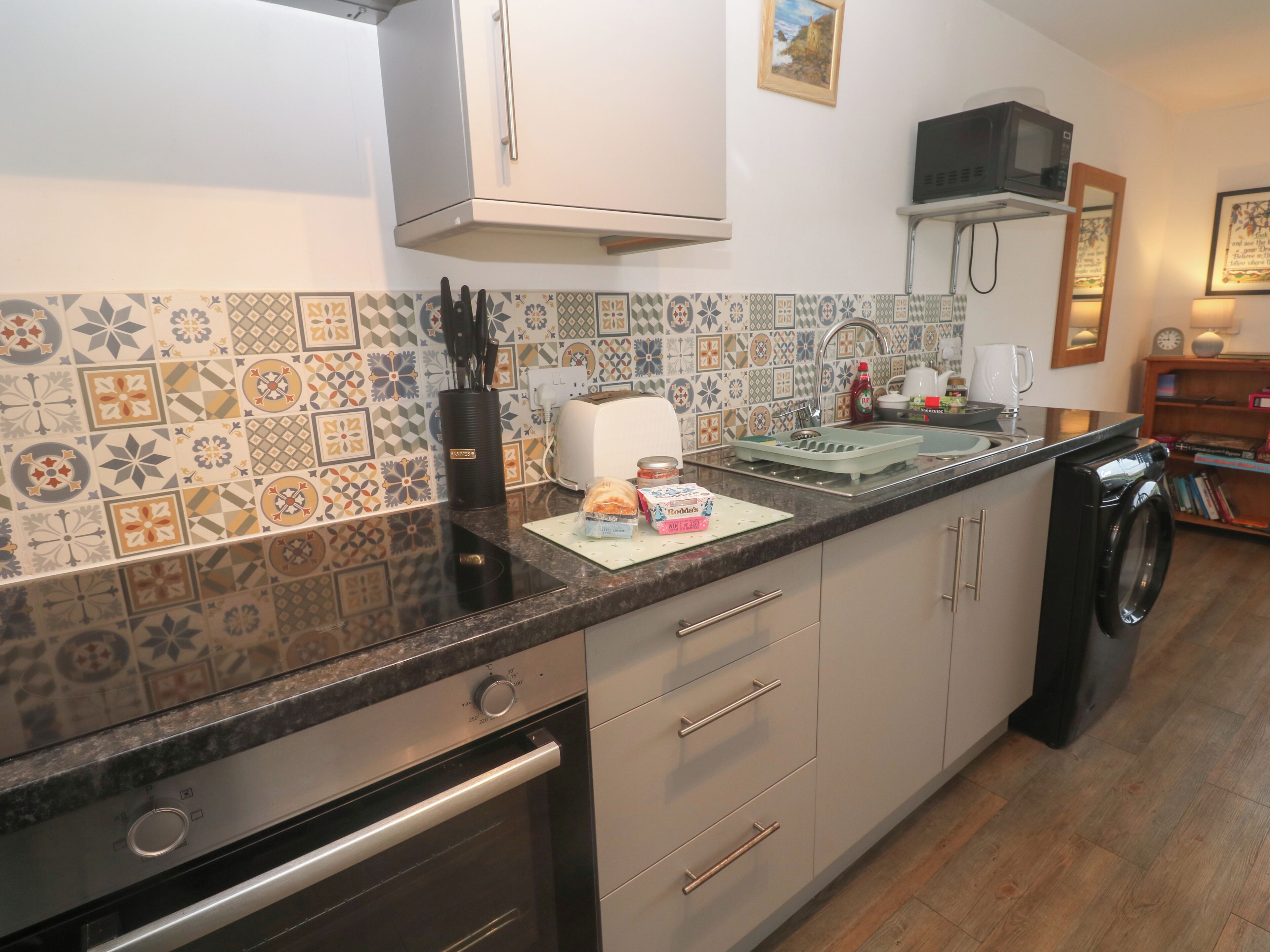A kitchen with a tiled backsplash, a microwave, a toaster, and a washing machine.