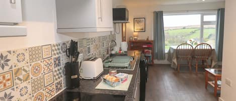 A kitchen with a toaster, a kettle, and a bread box on the counter.
