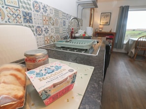 A kitchen with a countertop, a jar of strawberry conserve, a box of Roda's clotted cream, and a toaster. - Sandyfeet (Camborne)