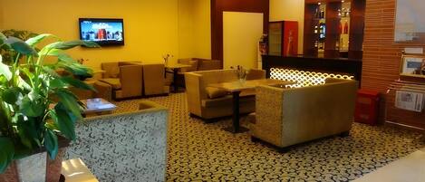 A lobby with sofas, a TV, a reception desk, and a patterned floor.