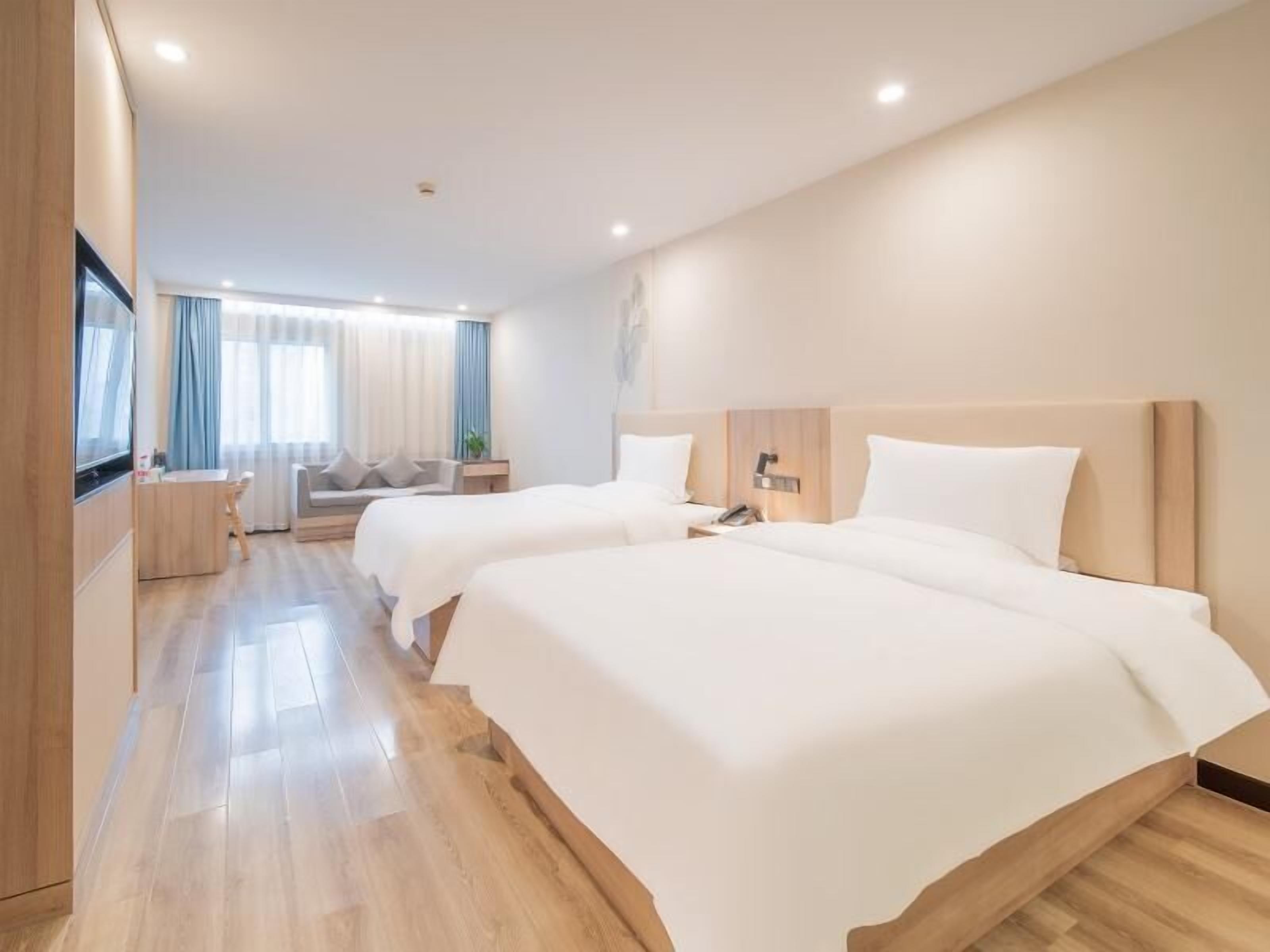 Una habitación de hotel moderna con dos camas grandes, un escritorio, una silla y un sofá.
