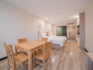 A hotel room with a wooden dining table and chairs, two single beds, and a large window.