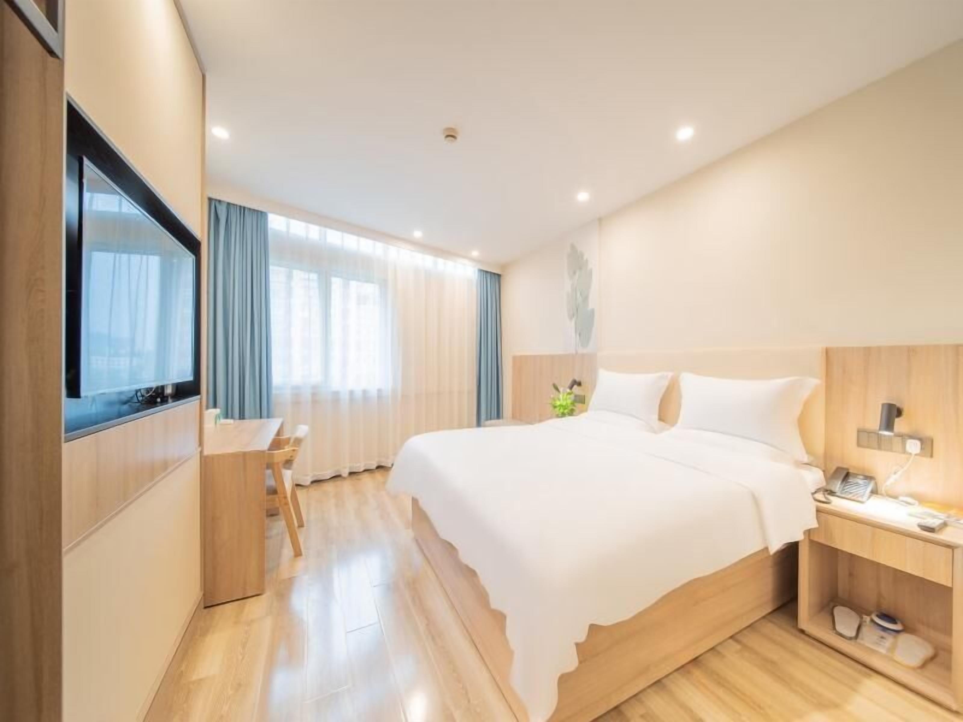 Une chambre d’hôtel moderne, dotée d’un grand lit, d’un bureau et d’une télévision.