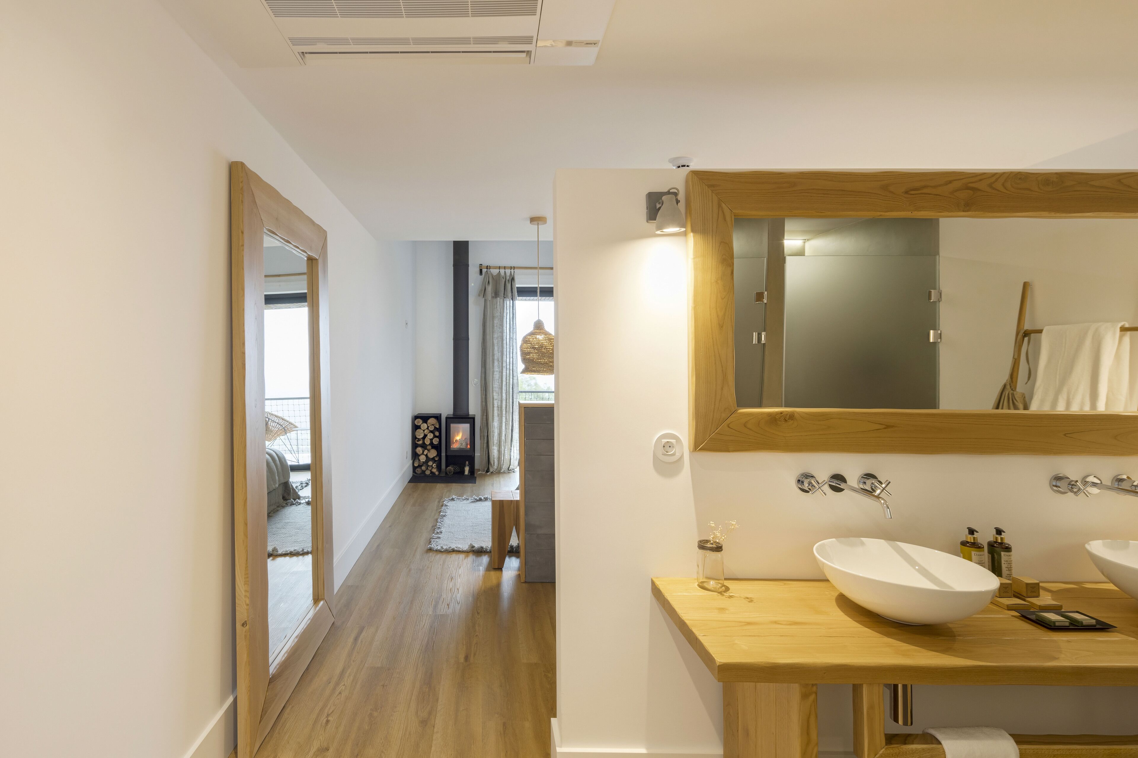 Ein modernes Badezimmer mit einem großen Spiegel, einem Holzkosmetikschrank und einem geräumigen weißen Waschbecken.