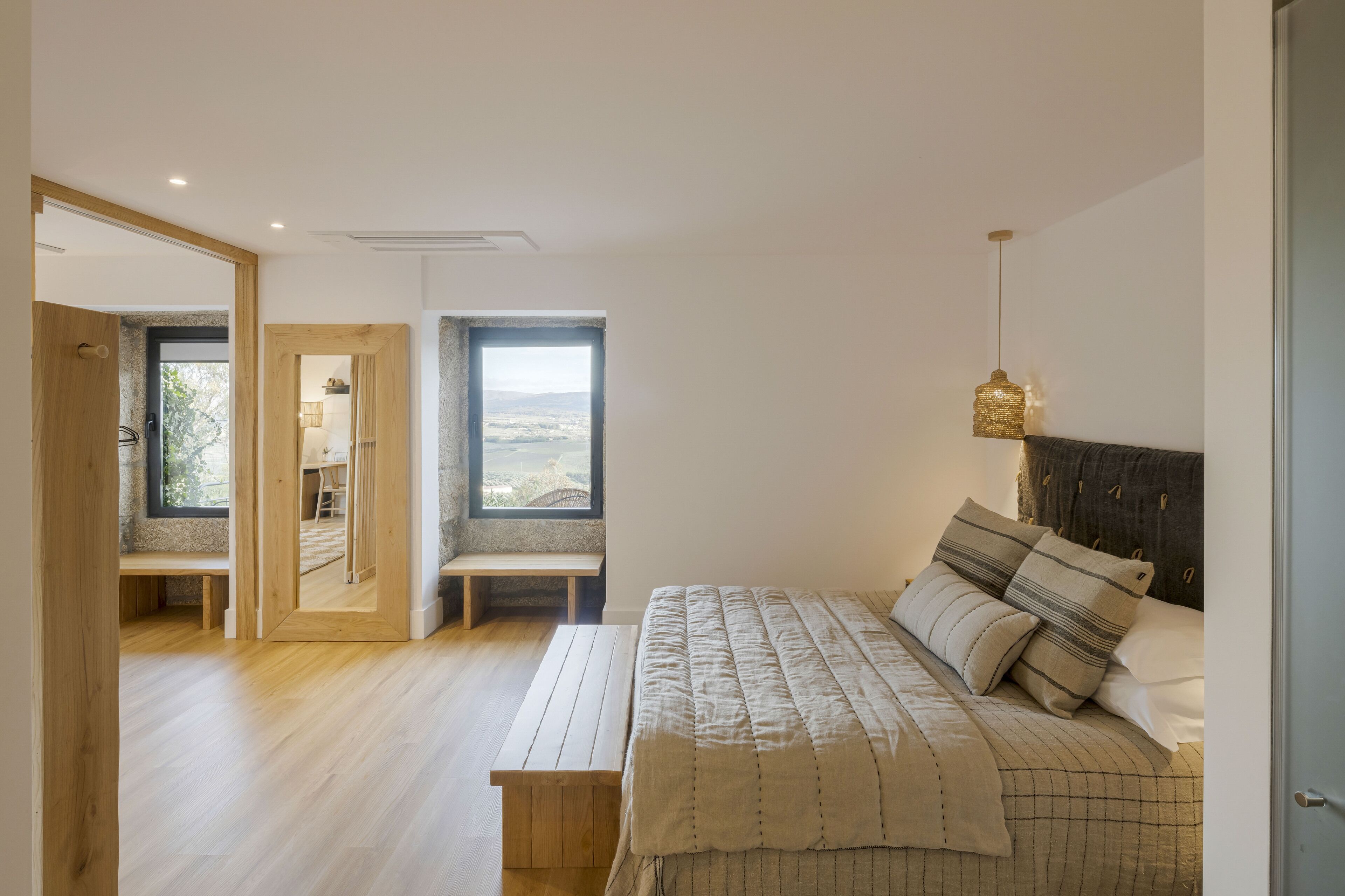 Un dormitorio con cama, banca y vistas por una ventana.