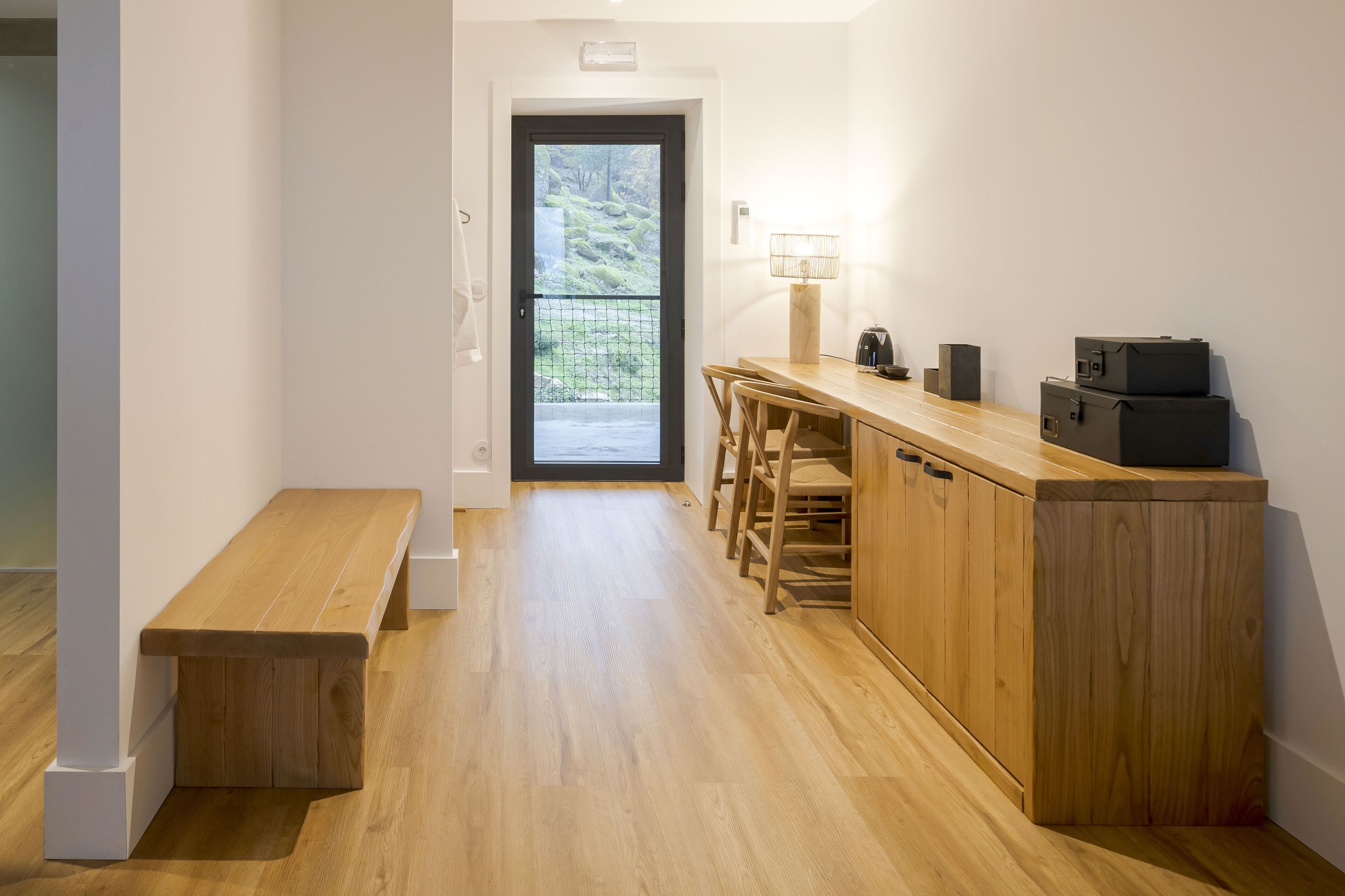 Una cocina moderna con encimeras de madera, una banqueta y vistas por la puerta.