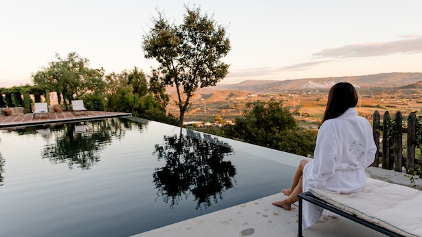 A person sitting by a pool with a view of a cityscape and hills. - TheVagar  (Belmonte)