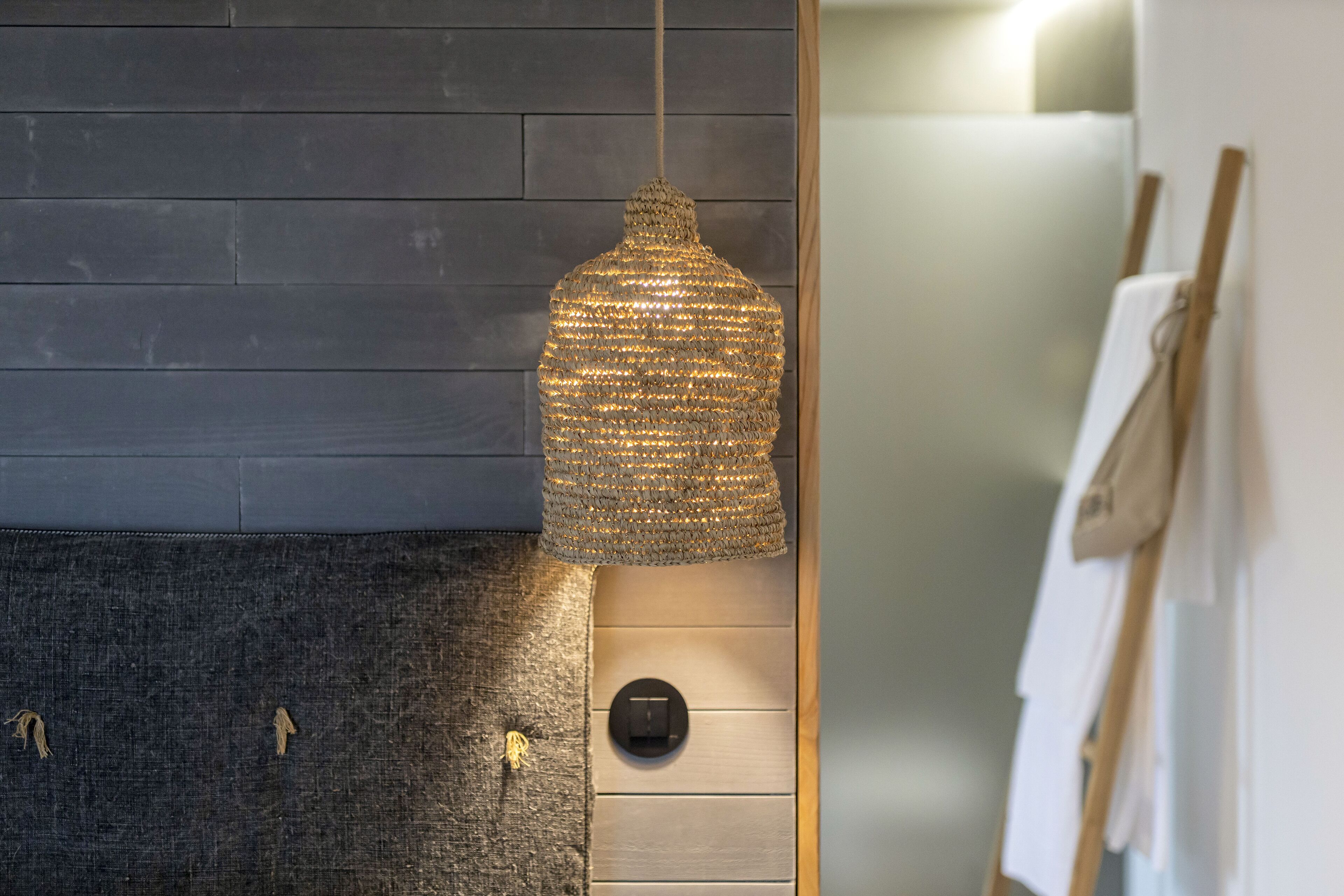 Un intérieur moderne avec un mur texturé, un luminaire suspendu et un panneau de commande.