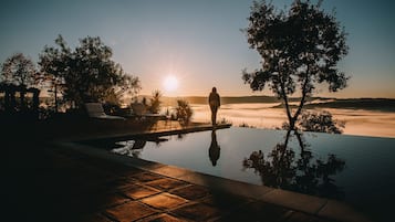 Una piscina al aire libre, sombrillas, sillones reclinables de piscina