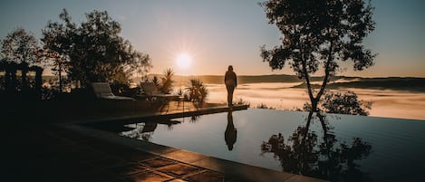 Una piscina al aire libre, sombrillas, sillones reclinables de piscina