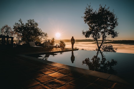 Una piscina al aire libre, sombrillas, sillones reclinables de piscina