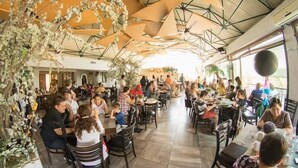 Un restaurant doté de nombreuses tables et chaises, entouré de grands parasols et agrémenté de plantes suspendues.