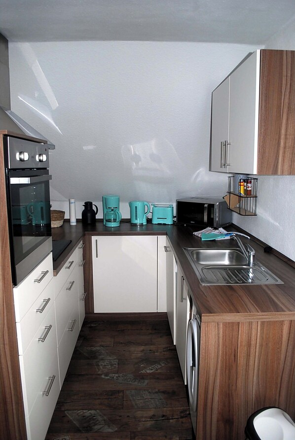 Compact kitchen with oven, microwave, toaster, and sink, perfect for self-catering.