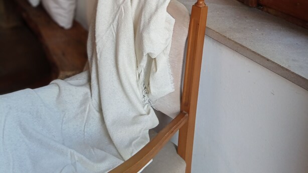 A wooden chair with a white cloth draped over it, positioned next to a window with a view of greenery outside. - Small cottage near the Sibillini Mountains (Marche)