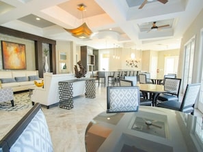 A modern hotel lobby with a seating area, a reception desk, and a dining space.