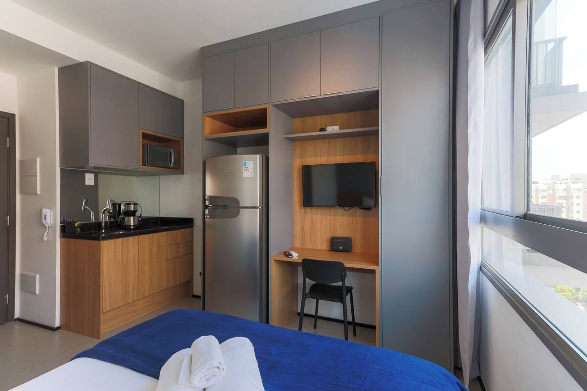Une chambre d’hôtel moderne équipée d’un lit, d’un bureau, d’une kitchenette et d’un téléviseur.