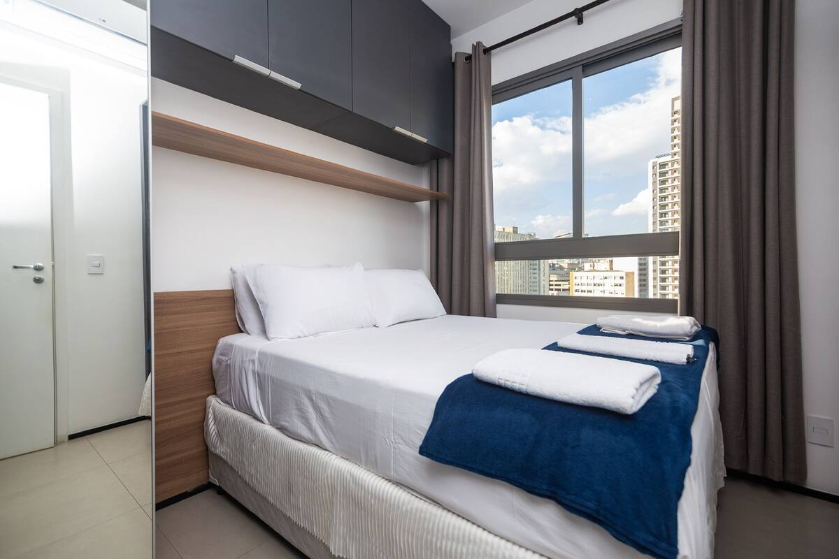 Une chambre d’hôtel moderne dotée d’un grand lit, d’une armoire intégrée et offrant une vue sur la ville.