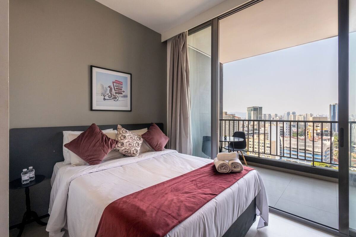 Une chambre d’hôtel moderne avec un grand lit, une vue sur la ville et un tableau encadré au mur.