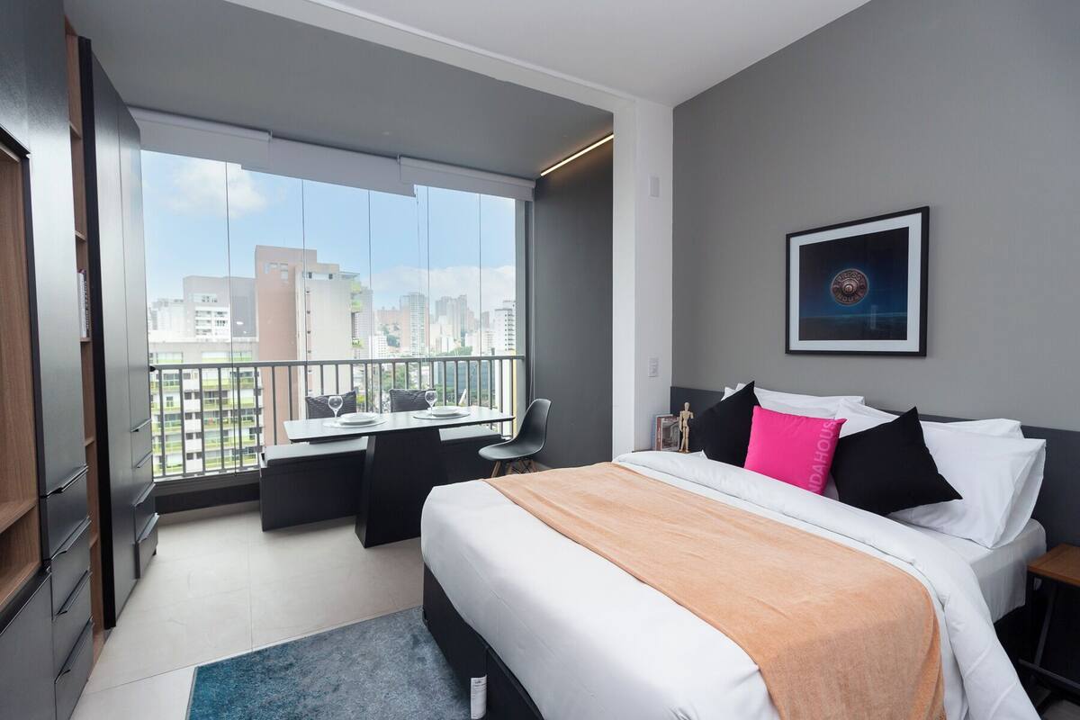 Une chambre d’hôtel moderne dotée d’un grand lit, d’un bureau et d’un balcon offrant une vue sur la ville.