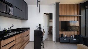 Eine moderne Küche mit schwarzen Arbeitsplatten, Holzschränken, einer schwarzen Kücheninsel und einer eingebauten Mikrowelle.