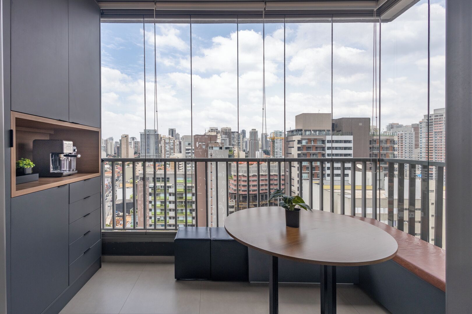 Un balcón moderno con vistas a la ciudad, una mesita y una cafetera.