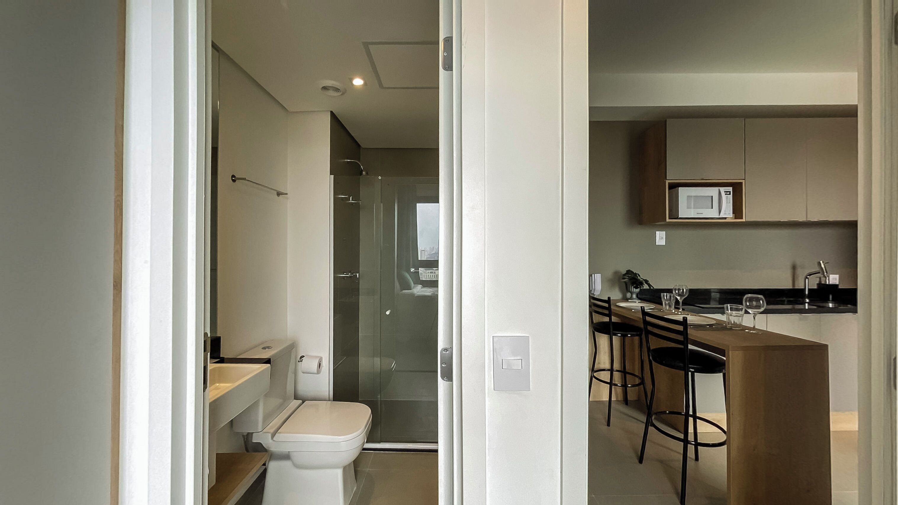 A modern kitchen with a microwave, bar stools, and a dining table.