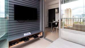 Ein modernes Wohnzimmer mit einem an der Wand befestigten Flachbildfernseher, einer Couch und einem Essbereich mit Tisch und Stühlen.