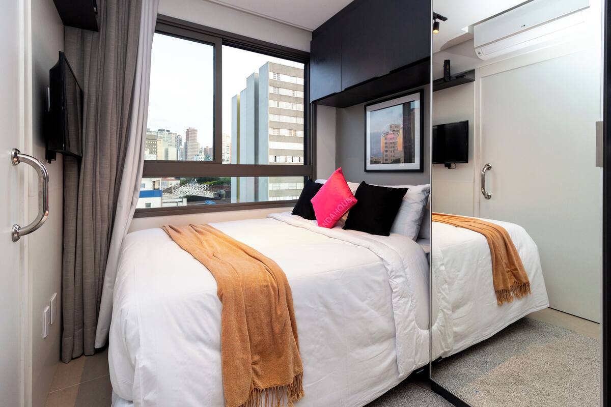 Une chambre d’hôtel avec un grand lit, deux oreillers, une couverture, une télévision et une vue sur la ville.