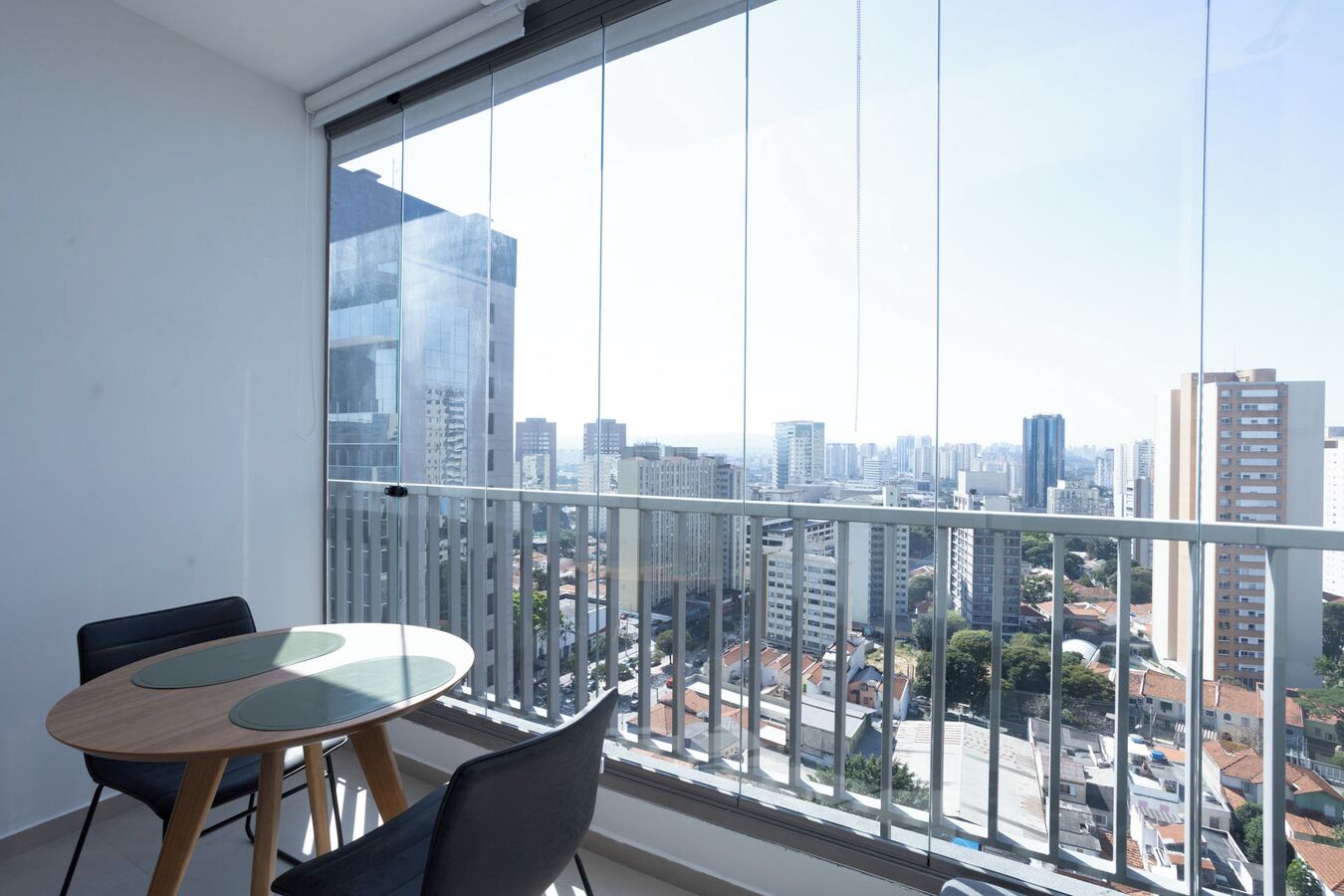 Un balcón con vistas a la ciudad, una mesa redonda y dos sillas.