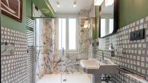 Et moderne badeværelse med et glasafskærmet brusebad, badekar og håndvask.