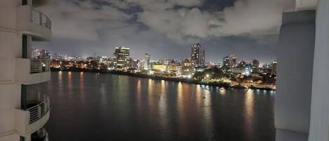 A nighttime cityscape with buildings along a waterfront.
