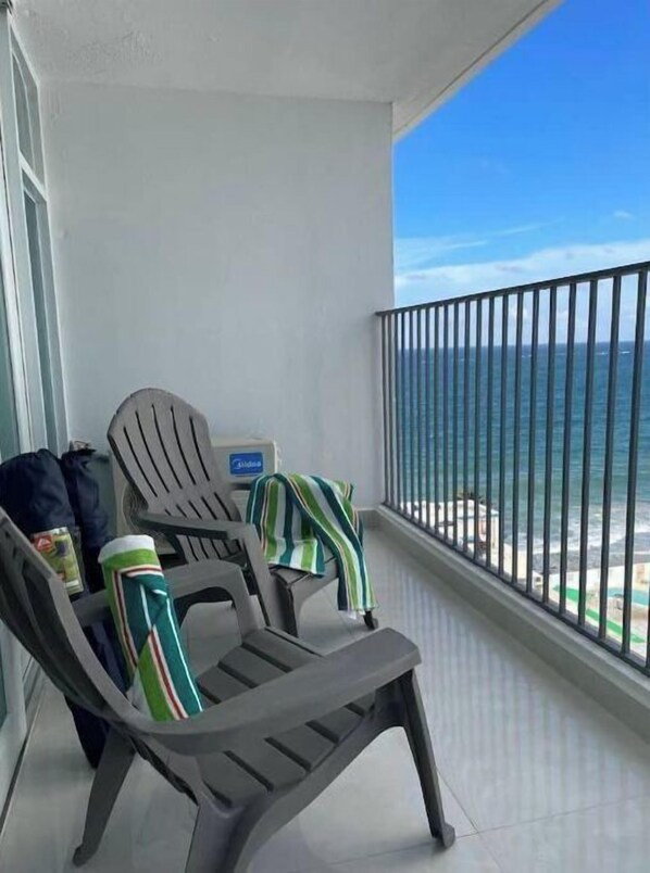 Un balcon équipé de deux fauteuils Adirondack, d’une serviette à rayures et d’un mini-bar.