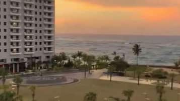 Un hotel con un edificio grande, una playa y palmeras.