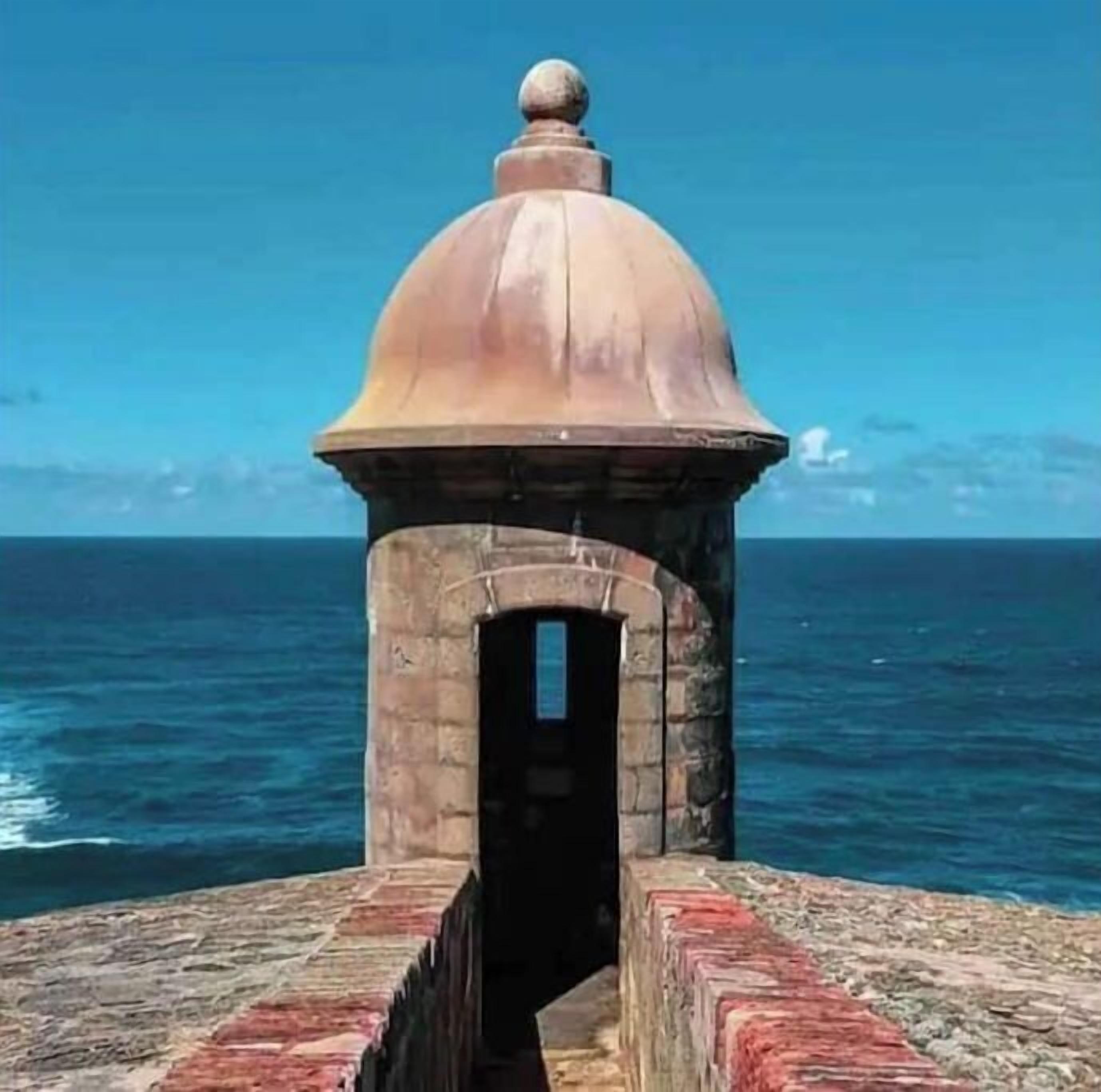 Una estructura de piedra con cúpula y entrada en arco, con vista a una masa de agua.