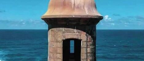 Una estructura de piedra con cúpula y entrada en arco, con vista a una masa de agua.