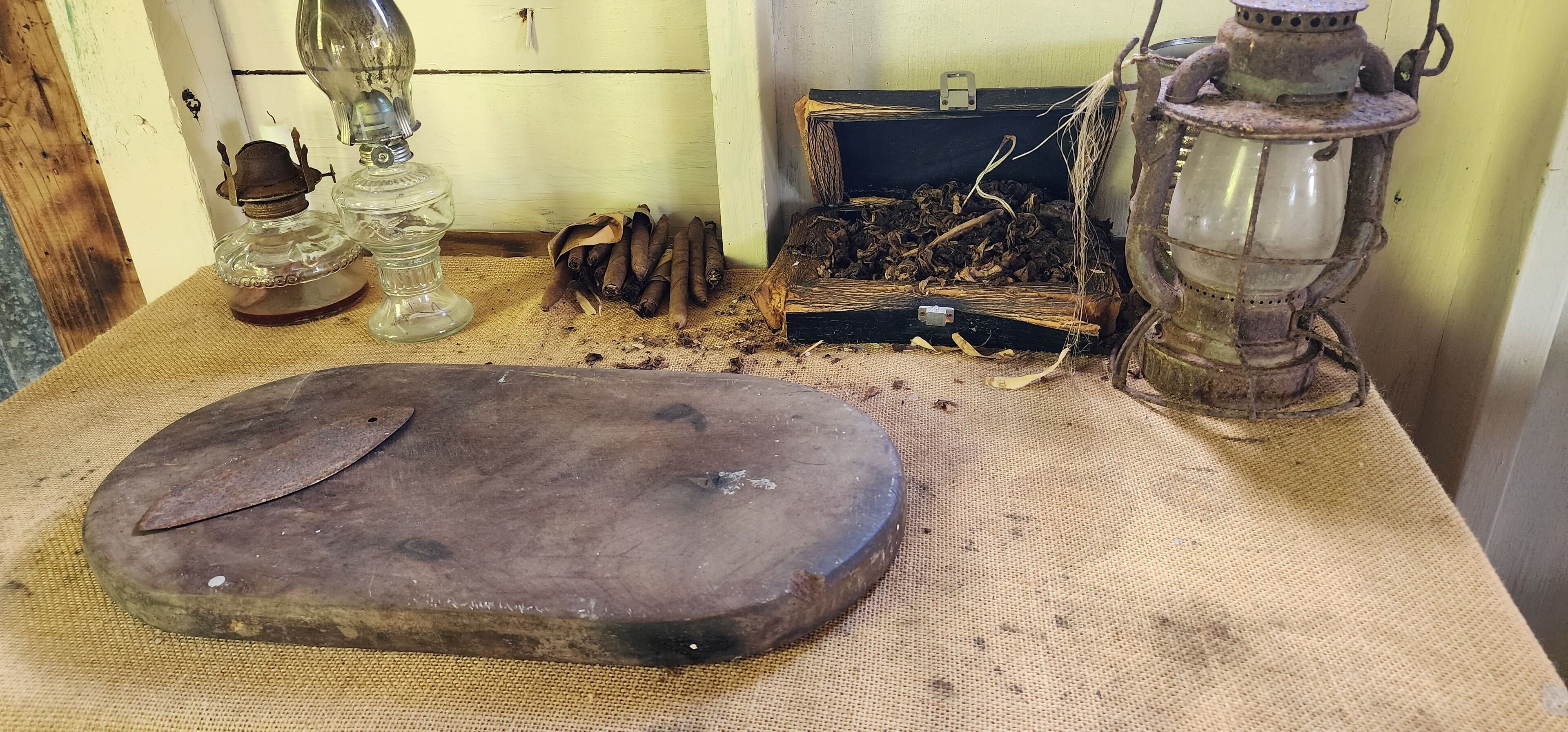 A rustic wooden chest, a lantern, and a pile of dried branches on a textured surface.