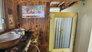 Een rustieke keuken met houten wanden, een fornuis met pannen en een houten deur.