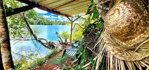 Un espacio de estar al aire libre rústico con vistas a un lago, una cesta tejida y un banco de madera.