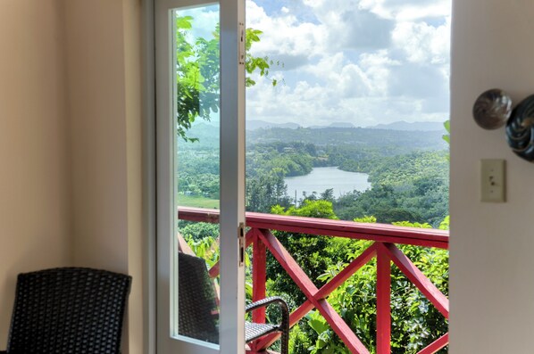 A balcony with a red railing overlooking a lush landscape with a lake and mountains. - LA CASITA DEL LAGO (Cidra)