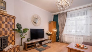 Un soggiorno con TV, mobile TV in legno e lampadario.